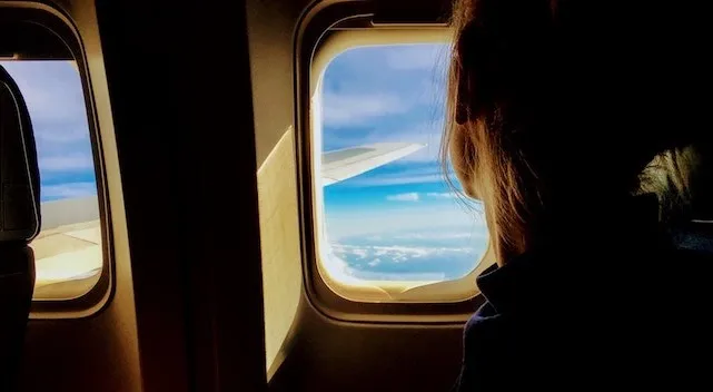 Woman traveling on airplane looks out the window
