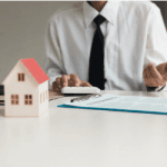 man explaining with a calculator and model house in front of him