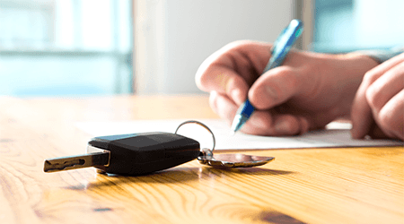 Man signing contract with car keys on the table