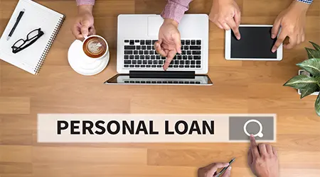 personal loans in a virtual search bar against laptop and tablet on a table