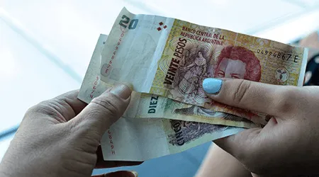 Female hand holding Argentina Peso bank notes