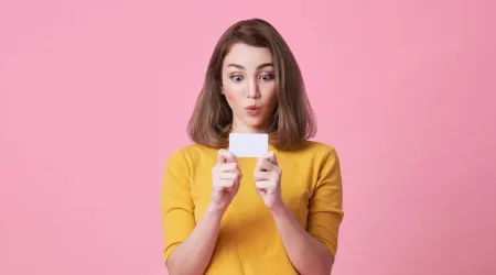 Girl looking surprised while holding credit card