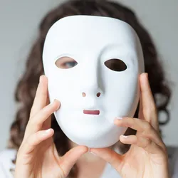Woman holding a white mask in front of her face